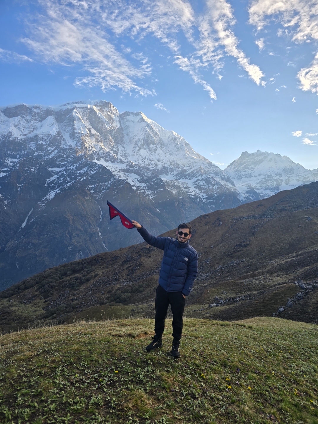 Utsav holding Nepal flag with Himalayan mountains in background
